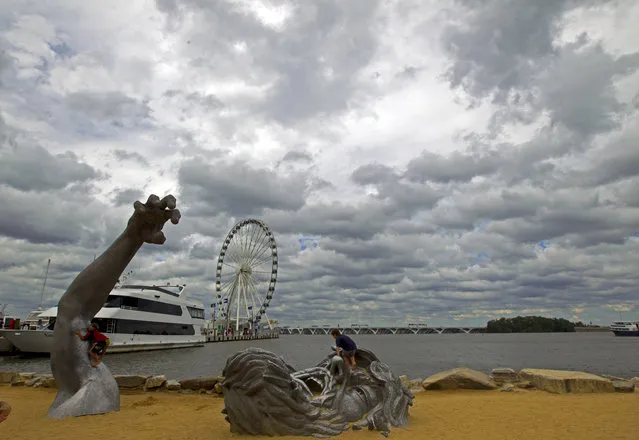 In this September 3, 2016, file photo, children play on J. Seward Johnson's sculpture, “The Awakening”, along the Potomac River waterfront at National Harbor, Md. Federal prosecutors say a man inspired by the Islamic State group stole a U-Haul truck with plans to drive it into a crowd at National Harbor, a convention and tourist destination just outside the nation's capital. (Photo by Jose Luis Magana/AP Photo/File)