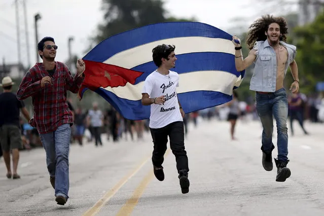 Fans run with a Cuban flag outside Ciudad Deportiva de la Habana sports complex where the Rolling Stones' free outdoor concert will take place today in Havana, March 25, 2016. (Photo by Ueslei Marcelino/Reuters)