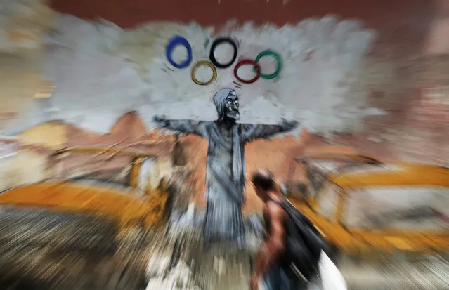 A man walks past a graffiti by Brazilian artist Paulo Ito depicting the statue of Christ the Redeemer juggling the Olympic rings in Rio de Janeiro, Brazil, January 16, 2017. (Photo by Nacho Doce/Reuters)