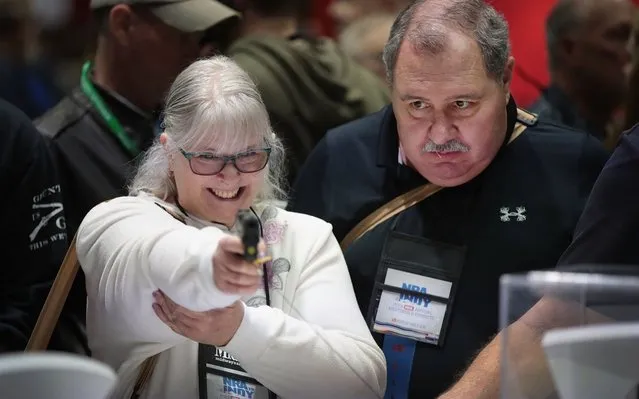 Patrick Haskins watches as his wife Barbara checks out a pistol in the Sig Sauer booth at the 148th NRA Annual Meetings & Exhibits on April 27, 2019 in Indianapolis, Indiana. The convention, which runs through Sunday, features more than 800 exhibitors and is expected to draw 80,000 guests. (Photo by Scott Olson/Getty Images)