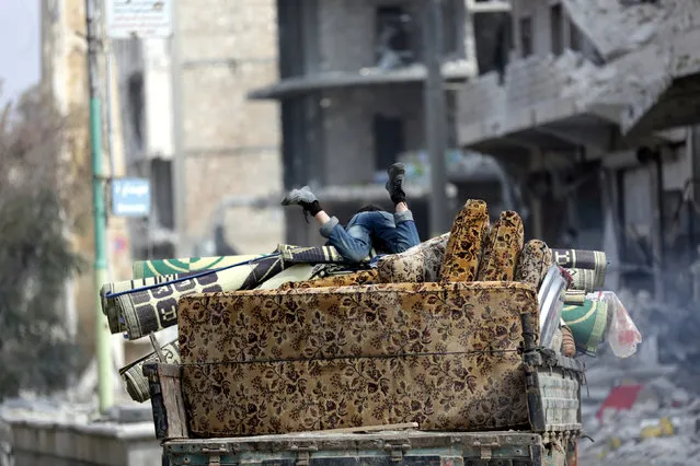 A boy rests over furniture stacked over a pick-up truck while driving through a damaged neighbourhood in the northern Syrian town of al-Bab, Syria March 4, 2017. (Photo by Khalil Ashawi/Reuters)