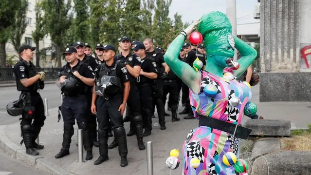 Police officers guard participants of the Equality March, organized by the LGBT community, in Kiev, Ukraine on June 23, 2019. More than 8,000 people turned out on June 23 for Kiev's annual Gay Pride parade amid tight security as far-right activists sought to disrupt the celebration, organisers said. The marchers, waving rainbow and Ukrainian flags and wearing colourful costumes, marched through the centre of the capital as thousands of police and National Guard troops stood by to ensure order. (Photo by Gleb Garanich/Reuters)