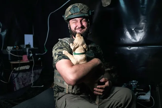 A soldier holds a puppy “Knop” in a dugout on April 27, 2024 in Kherson region, Ukraine. The 37th separate brigade of marines performs a combat mission in support of the infantry on the left bank of the Dnipro. The Ukrainian soldiers operate a 2S1 Gvozdika (“Carnation”) self-propelled howitzer, a Soviet-era gun that uses 122mm shells, which Ukraine procures from abroad. The Ukrainian government has told its Western allies that it is in desperate need of weapons and ammunition as it defends itself from the large-scale attack that Russia launched in February 2022. (Photo by Kostiantyn Liberov/Libkos/Getty Images)