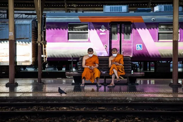 Thai monks look at their smart phones while waiting for a train at Hua Lamphong Railway Station on January 02, 2022 in Bangkok, Thailand. Thailand's Ministry of Public Health has provided free COVID-19 rapid testing to the public throughout the New Year's holiday weekend at Hua Lamphong Railway station in an effort to curb the spread of Omicron after holiday travel. (Photo by Lauren DeCicca/Getty Images)