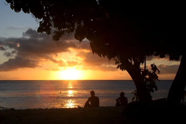 Surfers watch the sun set after surfing along the coast of Kiritimati Island, part of the Pacific Island nation of Kiribati, April 5, 2016. (Photo by Lincoln Feast/Reuters)