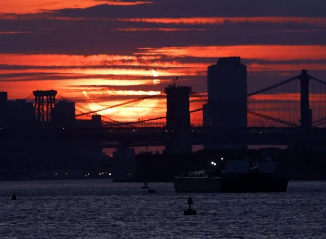 A partial solar eclipse rises behind the Brooklyn Bridge and other east river crossings in Manhattan from Bayonne, New Jersey on Thursday, June 10, 2021. (Photo by John Angelillo/UPI/Alamy Live News)
