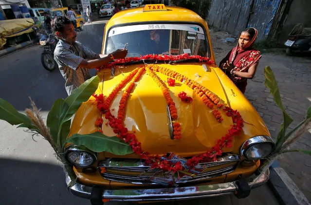 A taxi driver and his wife offer prayers in front of their taxi during the Vishwakarma Puja, or the festival of the Hindu deity of architecture and machinery, in Kolkata, India, September 18, 2019. (Photo by Rupak De Chowdhuri/Reuters)