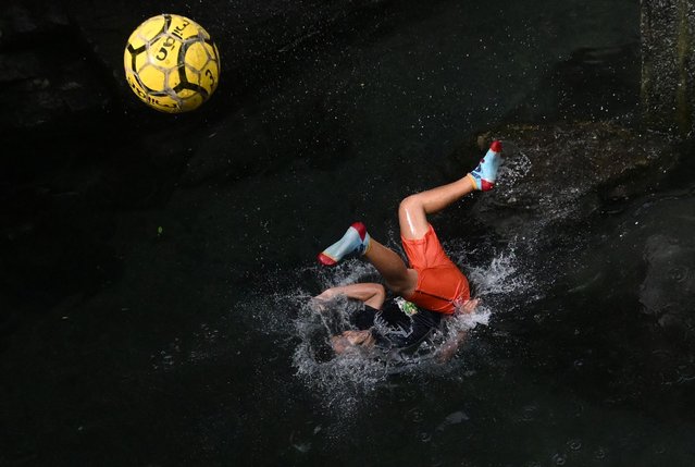 A boy plays with a football in the water during a warm day at the El Cuilio pool in San Salvador, El Salvador on June 28, 2024. (Photo by Marvin Recinos/AFP Photo)