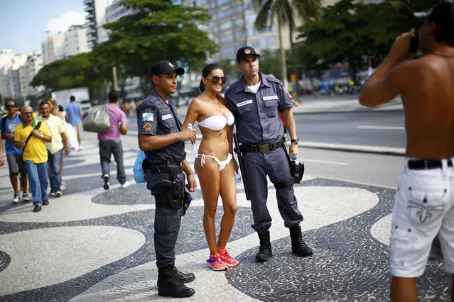 A woman poses with police officers near Copacabana Beach ahead of the 2014 World Cup in Rio de Janeiro, June 12, 2014. (Photo by Darren Staples/Reuters)