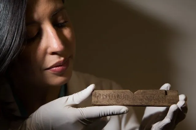 MOLA (Museum of London Archaeology) archaeologist Luisa Duarte poses for a picture holding a Roman waxed writing tablet containing the earliest written reference to London, dated AD 65/70-80, which translated reads “Londinio Mogontio” (in London, to Mogontius...), at  Bloomberg's offices in central London on June 1, 2016, during a presentation of artefacts found beneath Bloomberg's new European headquarters. A trove of Roman writing tablets has been unearthed in the heart of London, archaeologists announced on June 1, shedding light on the commerce-driven life in what became the City of London financial hub. (Photo by Daniel Leal-Olivas/AFP Photo)