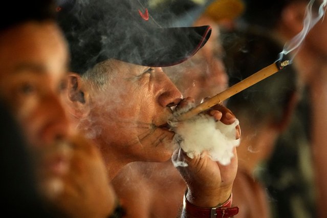 Chief Sergio Muti Tembe smokes his traditional cigar during the the Wyra'whaw coming-of-age festival in the Ramada ritual center, in Tenetehar Wa Tembe village, located in the Alto Rio Guama Indigenous territory in Para state, Brazil, Saturday, June 10, 2023. Known as the Menina Moca in Portuguese, the three-day festival is for adolescent boys and girls in Brazil's Amazon. (Photo by Eraldo Peres/AP Photo)