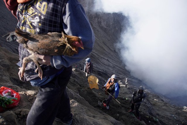 Villagers stand on the slopes near the crater of Mount Bromo as they wait for Hindu worshippers to throw offerings while smoke and ash rises from the volcano during the Yadnya Kasada ceremony in Probolinggo, East Java province, Indonesia on June 5, 2023. (Photo by Irfan Sumanjaya/Antara Foto via Reuters)