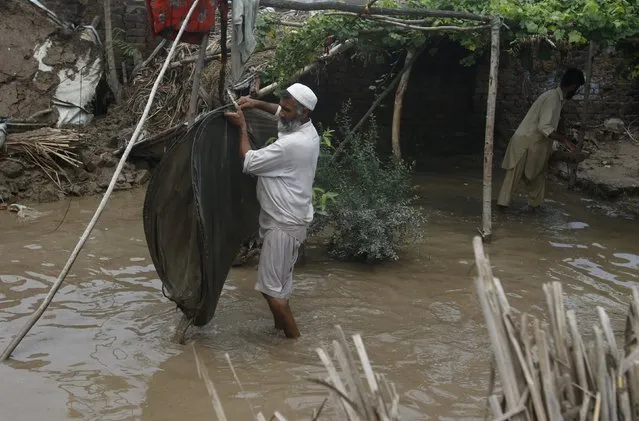 A man retrieves belongings from his flooded house at Camp Koruna area of Nowshera District, northwestern Pakistan, August 3, 2015. Flash flooding caused by torrential monsoon rains affected hundreds of thousands of people, according to aid agencies, with further monsoon downpours expected in the coming days. (Photo by Khuram Parvez/Reuters)