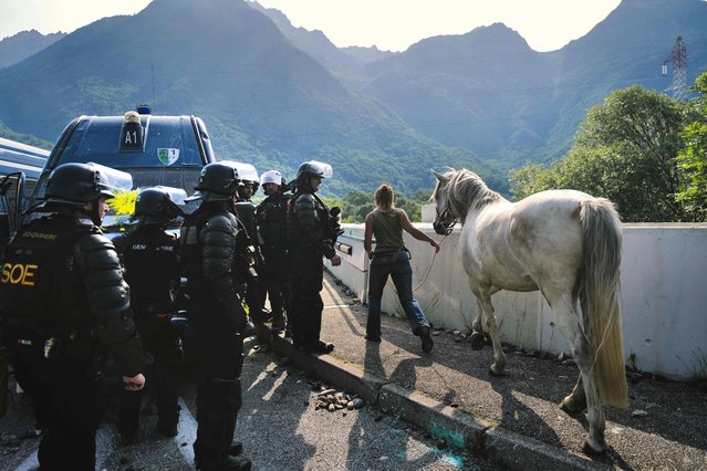 French gendarmes let pass a woman with her horse as they operate during a demonstration against the construction of a high-speed rail line between Lyon and Torino, in La Chapelle, near Modane, in the French Alps' Maurienne valley, on June 17, 2023. Hundreds of oponents to the Lyon-Torino high-speed rail line demonstrated on June 17 despite a ban on the gathering, of which the details are yet to be determined and despite a heavy police presence in the valley. They set up a makeshift camp on land lent by the municipality of La Chapelle, outside the ban zone announced the day before by the Savoie prefecture. (Photo by Olivier Chassignole/AFP Photo)