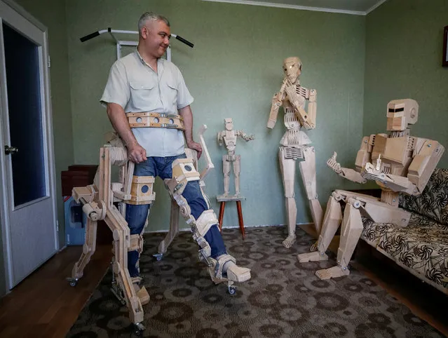 Dmitry Balandin uses a wooden external prosthesis as he plays with his wooden models Centurion (R), Amazon (2nd R) and Kid in his flat in Zaporizhzhya, Ukraine, Ukraine, July 5, 2017. It took Balandin, who works as a crane operator, eighteen months to build models from 1750 parts. Balandin says he does not use blueprints and designs the parts as he works on them. He says he would love to build metal models but that is impossible to do so in his small apartment. He plays with models as a child would play with a doll or Lego toy and he hopes to have them displayed at exhibitions and galleries. Picture taken July 5, 2017. (Photo by Gleb Garanich/Reuters)