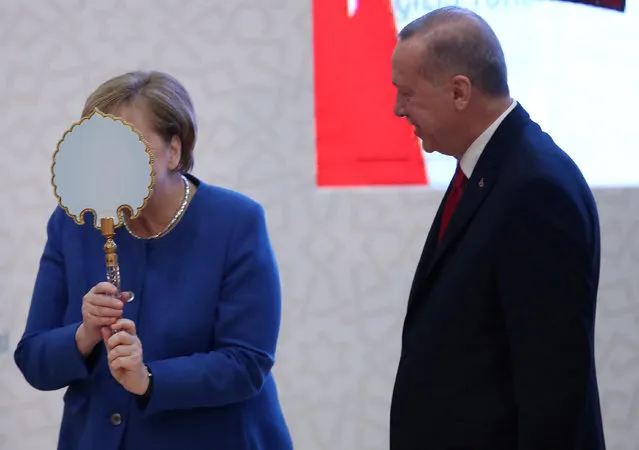 German Chancellor Angela Merkel receives a gift from Turkish President Tayyip Erdogan during the official opening ceremony of Turkish-German University's new campus in Istanbul, Turkey, January 24, 2020. (Photo by Tolga Bozoglu/Pool via Reuters)
