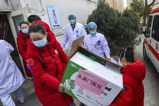 Doctors watch as donated medical supplies from Beijing are unloaded at a hospital in Wuhan in central China's Hubei Province, Thursday, January 30, 2020. China counted 170 deaths from a new virus Thursday and more countries reported infections, including some spread locally, as foreign evacuees from China's worst-hit region returned home to medical observation and even isolation. (Photo by Chinatopix via AP Photo)