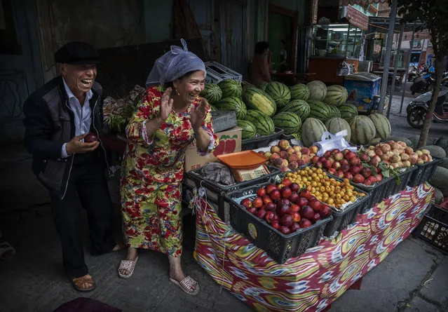 Ethnic Uyghurs joke with a customer at their fruit stall on June 28, 2017 in the old town of Kashgar, in the far western Xinjiang province, China. (Photo by Kevin Frayer/Getty Images)