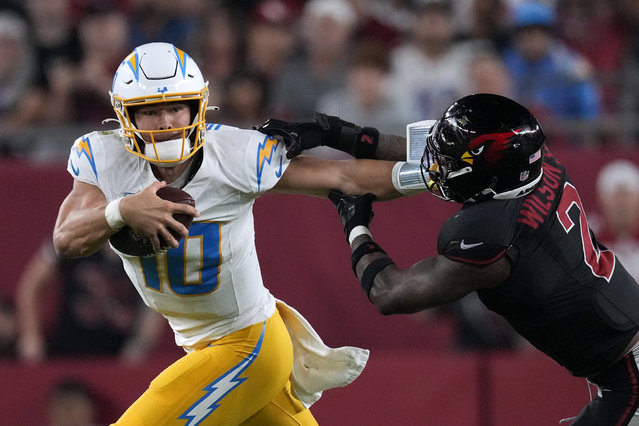 Los Angeles Chargers quarterback Justin Herbert (10) runs from Arizona Cardinals linebacker Mack Wilson Sr. (2) during the second half of an NFL football game, Monday, October 21, 2024, in Glendale Ariz. (Photo by Matt York/AP Photo)