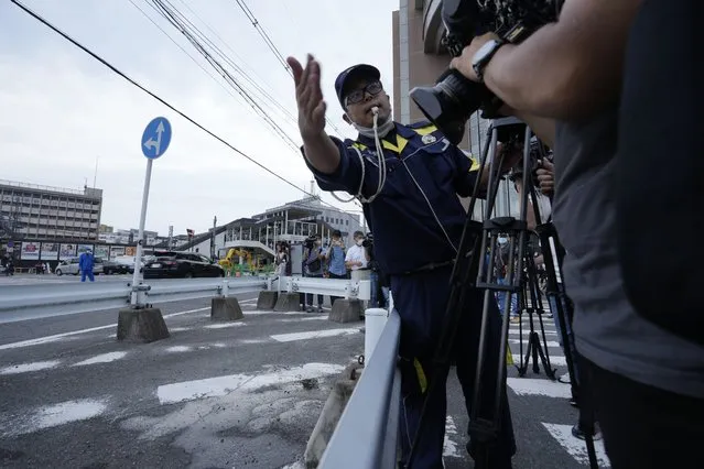 A Nara Police officer tries to move the media from the area where the former Prime Minister Shinzo Abe was shot while delivering his speech to support the Liberal Democratic Party's candidate during an election campaign in Nara, Friday, July 8, 2022. (Photo by Hiro Komae/AP Photo)