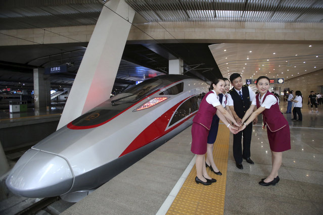 In this June 26, 2017 file photo, railway workers pose for photos with the Fuxing, China's latest high speed train capable of reaching 400kph (248mph) during its maiden service from Beijing. China is relaunching the world's fastest bullet trains in September 2017, running at 350 kilometers (217 miles) per hour. China first ran trains at 350 kilometers per hour in August 2008, but cut speeds back to 250-300 kilometer per hour in 2011 following a two-train collision near the city of Wenzhou that killed 40 people and injured 191. (Photo by Chinatopix via AP Photo)