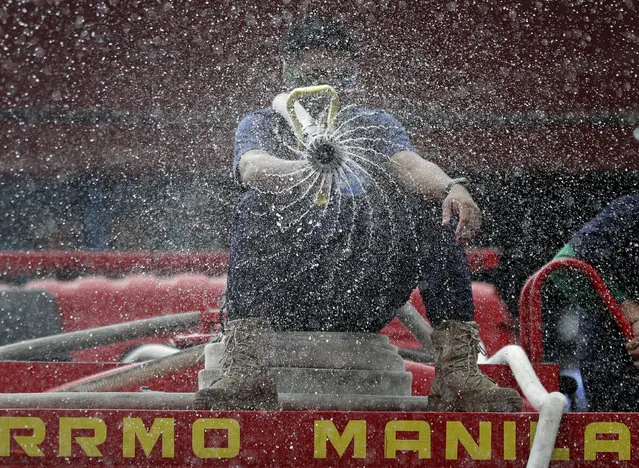 Firemen spray disinfectants outside a public market in Manila, Philippines on Wednesday, March 11, 2020. For most people, the new coronavirus causes only mild or moderate symptoms, such as fever and cough. For some, especially older adults and people with existing health problems, it can cause more severe illness, including pneumonia. (Photo by Aaron Favila/AP Photo)