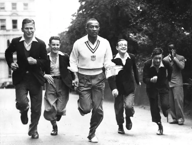 Olympic gold medalist Jesse Owens finds himself the object of extreme interest on the part of a group of boys, as he trots back to his quarters through Hyde Park in London, August 19, 1936. (Photo by AP Photo)