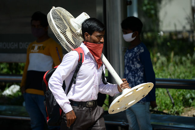 A migrant worker carrying a fan walks along a road as his leaves India's capital for his home during a government-imposed nationwide lockdown as a preventive measure against the COVID-19 coronavirus, in New Delhi on March 29, 2020. (Photo by Sajjad Hussain/AFP Photo)