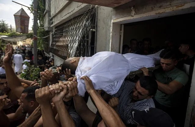 Mourners carry the body of Palestinian Tamim Hijazi, who was killed in an Israeli air strike, during his funeral in Khan Yunis in the southern Gaza Strip, Saturday, August 6, 2022. (Photo by Yousef Masoud/AP Photo)