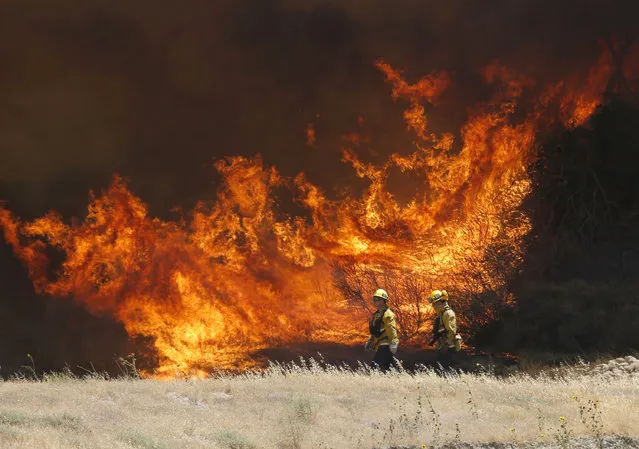 A hillside erupts in flame as a wildfire burns in Placerita Canyon in Santa Clarita, Calif., Monday, July 25, 2016. The smoky fire tore through drought-ravaged brush that hadn't burned in decades amid a sweltering heat wave and exploded over the weekend. (Photo by Nick Ut/AP Photo)