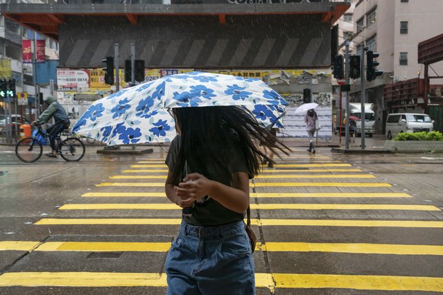 People holding umbrellas under strong wind walk pass a crosswalk as tropical storm Ma-on passes Hong Kong, Thursday, August 25, 2022. (Photo by Anthony Kwan/AP Photo)