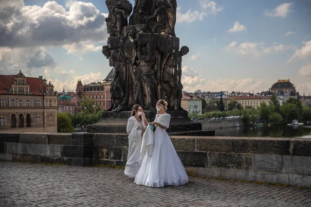 Models, wearing protective face masks and wedding dresses, walk on the Charles Bridge as they take part in a commercial shot in Prague, Czech Republic, 05 May 2020. Czech government decided to ease the restrictive measures declared to quell the spread of the pandemic COVID-19 disease caused by the SARS-CoV-2 coronavirus. (Photo by Martin Divisek/EPA/EFE)