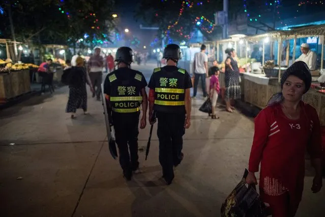 This picture taken on June 25, 2017 shows police patrolling in a night food market near the Id Kah Mosque in Kashgar in China's Xinjiang Uighur Autonomous Region, a day before the Eid al-Fitr holiday. The increasingly strict curbs imposed on the mostly Muslim Uighur population have stifled life in the tense Xinjiang region, where beards are partially banned and no one is allowed to pray in public. Beijing says the restrictions and heavy police presence seek to control the spread of Islamic extremism and separatist movements, but analysts warn that Xinjiang is becoming an open air prison. (Photo by Johannes Eisele/AFP Photo)