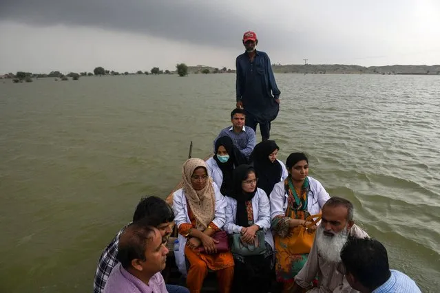 A team of doctors travel to flooded areas in a boat, following rains and floods during the monsoon season, in Manjhand town, in Jamshoro, Pakistan on September 12, 2022. (Photo by Yasir Rajput/Reuters)