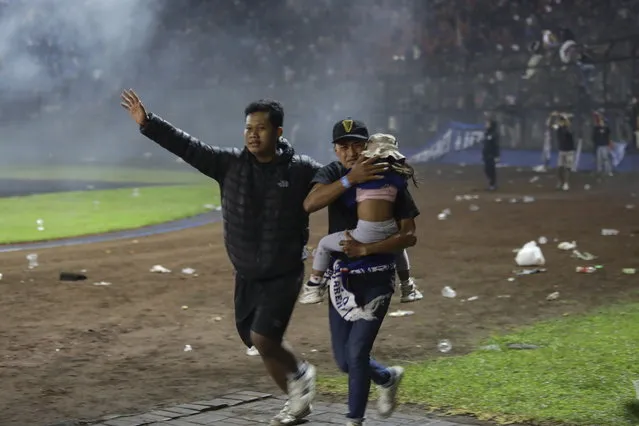 Soccer fans evacuate a girl during a clash between fans at Kanjuruhan Stadium in Malang, East Java, Indonesia, 01 October 2022. At least 127 people including police officers were killed mostly in stampedes after a clash between fans of two Indonesian soccer teams, according to the police. (Photo by H. Prabowo/EPA/EFE)