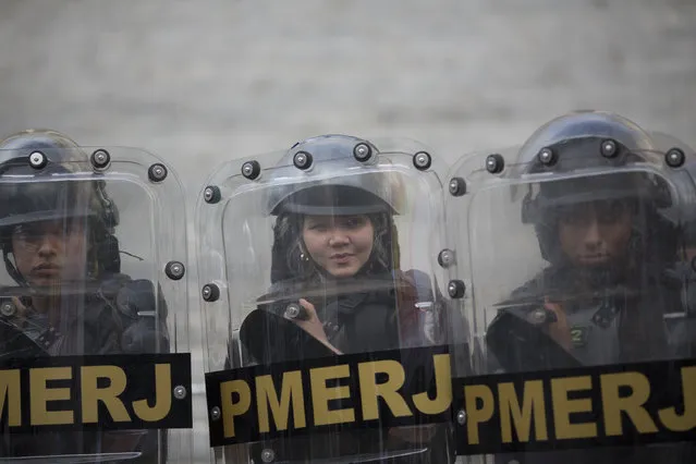 In this Wednesday, November 8, 2017 photo, police stand guard outside the state legislative assembly during a protest in Rio de Janeiro, Brazil. Hundreds of police, firefighters and health employees were among the demonstrators protesting that the state hasn't paid their salaries and pensions on time. (Photo by Silvia Izquierdo/AP Photo)