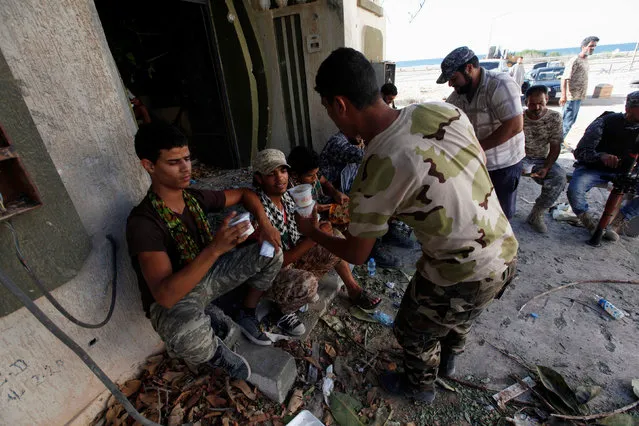 Fighters from Libyan forces allied with the U.N.-backed government receive meals during a battle with Islamic State fighters in neighborhood Number One in Sirte, Libya August 17, 2016. (Photo by Ismail Zitouny/Reuters)