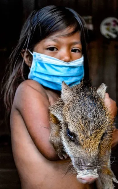 A Colombian Tikuna indigenous girl poses wearing a face mask, amid concerns of the COVID-19 coronavirus, in Leticia, department of Amazonas, Colombia on June 8, 2020. Mostly indigenous, unpopulated and poor, Colombia's Amazon suffers silently, deep in the jungle, from the pandemic. Its proximity to Brazil, the largest source of the virus in Latin America, opened a corridor of infection that further undermined its precarious health system. (Photo by Tatiana de Nevo/AFP Photo)