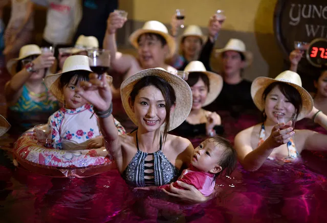 A mother raise her glass filled with 2017 Beaujolais Nouveau wine as she holds her child in a colored hot water “wine bath” at Hakone Kowakien Yunessun hot spring resort in Hakone, west of Tokyo, Japan, 16 November 2017, on the day of the Beaujolais Nouveau official release. With Germany and the United States, Japan is a major market for the Beaujolais Nouveau. (Photo by  Franck Robichon/EPA/EFE)