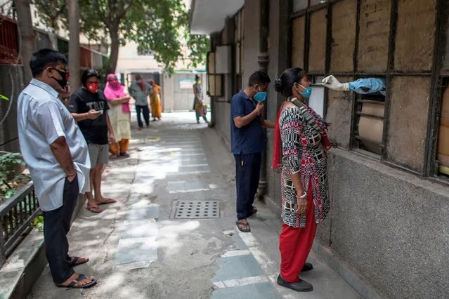 A health official (R) collects a swab sample from a woman to test for the COVID-19 coronavirus at a temporary free testing facility set up in a school after authorities eased restrictions imposed as a preventive measure against the spread of the COVID-19 coronavirus, in New Delhi on June 19, 2020. (Photo by Xavier Galiana/AFP Photo)