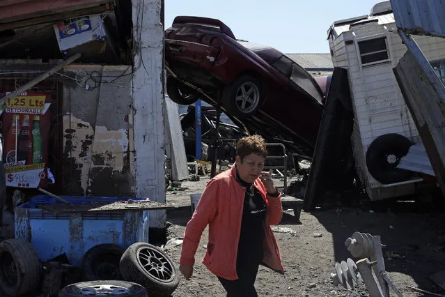 A woman walks past a car, propped up in mid-air, among the debris left behind by an earthquake-triggered tsunami in the coastal town of Coquimbo, Chile, Thursday, September 17, 2015. Several coastal towns were flooded from small tsunami waves set off by late Wednesday's quake, which shook the Earth so strongly that rumbles were felt across South America. (Photo by Luis Hidalgo/AP Photo)