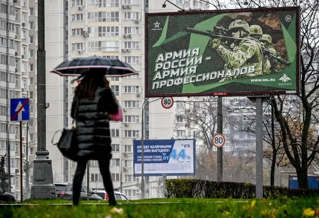 A pedestrian walks past a poster displaying Russian soldiers with a slogan reading “Army of Russia – Army of professionals” decorating a street in Moscow on October 24, 2022. (Photo by Yuri Kadobnov/AFP Photo)