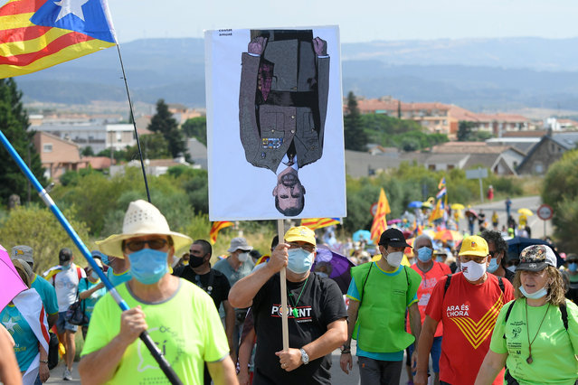 A man carries an upside-down portrait of King Felipe VI of Spain during an anti-monarchy march in Monasterio de Poblet on July 20, 2020, coinciding with a visit of the Spanish royals to the Royal Abbey of Santa Maria de Poblet. (Photo by Lluis Gene/AFP Photo)