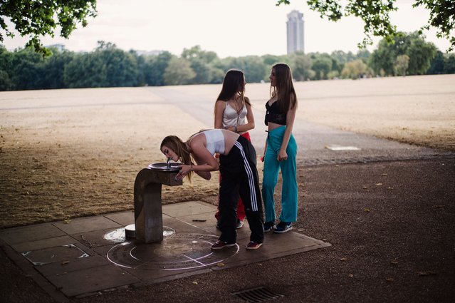 Teenage girls at a drinking fountain in Hyde Park in Central London on August 9, 2022 after weeks with no significant rain and unprecedented high temperatures. Many parts of southern England and Wales are facing drought conditions and preparing for emergency water measures. (Photo by Sarah Lee/The Guardian)