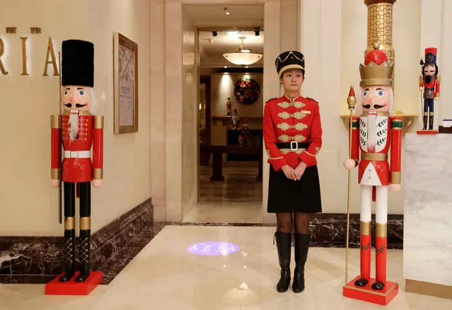 A waitress stands next to Christmas toy soldier decorations at a hotel in Beijing, China on December 8, 2017. (Photo by Jason Lee/Reuters)