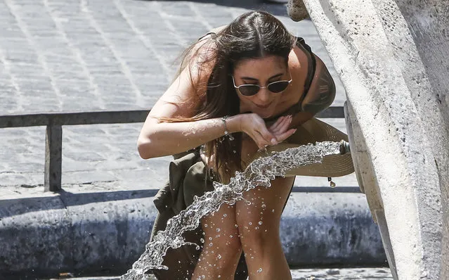 A woman drinks at the Barcaccia fountain, built between 1627 and 1629 by Pietro Bernini, possibly with the help of his son Gian Lorenzo, in downtown Rome, Friday, July 31, 2020. The first heat wave of the summer will last at least until Saturday, bringing temperatures over 34 Celsius (104 Fahrenheit). (Photo by Riccardo De Luca/AP Photo)