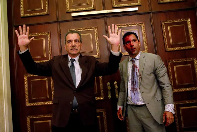 Opposition lawmaker Luis Stefanelli gestures next to fellow opposition lawmaker Leonardo Regnault after a group of government supporters burst into Venezuela's opposition-controlled National Assembly during a session, in Caracas, Venezuela July 5, 2017. (Photo by Carlos Garcia Rawlins/Reuters)
