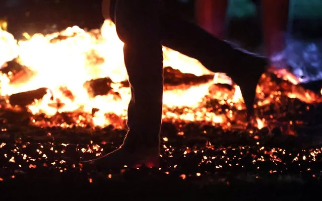 A person walks through fire cinders during a firewalking class in Alnwick, Britain on October 14, 2022. (Photo by Lee Smith/Reuters)