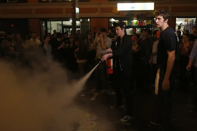 A woman extinguishes a bonfire during a street celebration in San Francisco, California October 29, 2014. (Photo by Stephen Lam/Reuters)