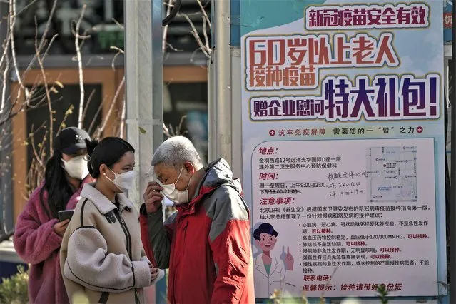 An elderly man puts on his mask after getting his routine COVID-19 throat swab at a coronavirus testing site displaying a poster which encourages elderly citizen to get vaccination in Beijing, Sunday, December 4, 2022. (Photo by Andy Wong/AP Photo)